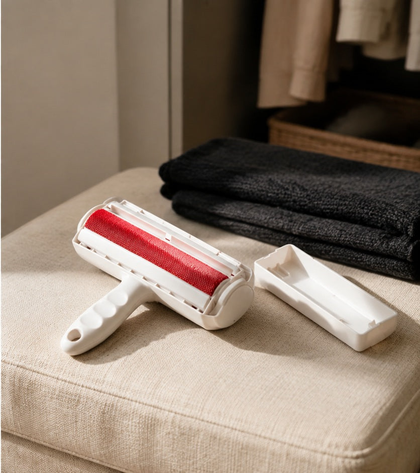 Reusable pet hair remover roller and base tray on a linen ottoman