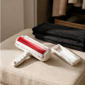 Reusable pet hair remover roller and base tray on a linen ottoman